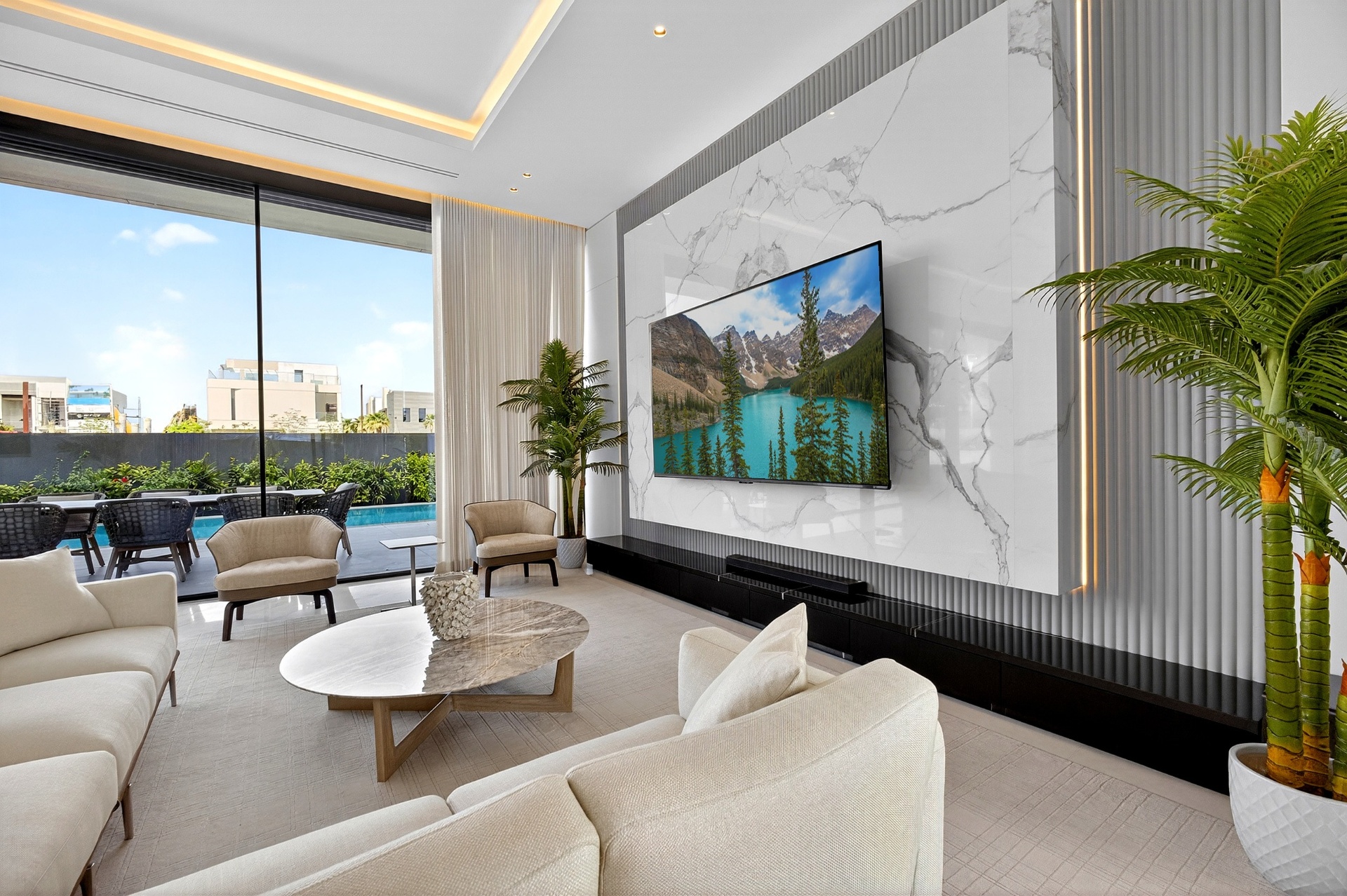 Villa A9 lounge with marble media wall, tall palms, and soft neutral seating